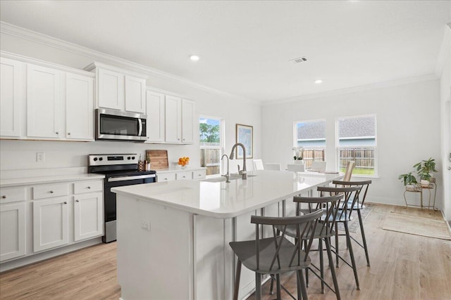613 Las Roblas Grande Dr, Santa Rosa Beach, FL 32459 - kitchen featuring stainless steel appliances, a sink, a center island with sink, crown molding, and light wood-type flooring