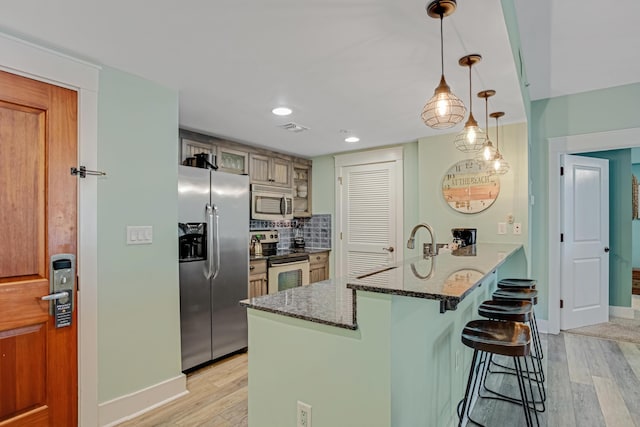 kitchen featuring appliances with stainless steel finishes, a breakfast bar, light wood-style floors, baseboards, and recessed lighting