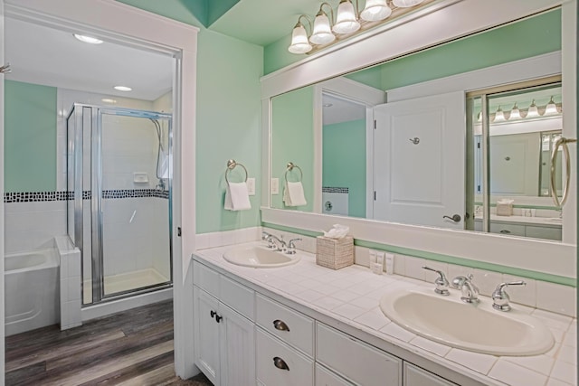 bathroom featuring a shower stall, double vanity, wood finished floors, and a bathtub