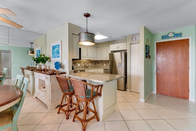30 Moreno Point Rd Unit 206B, Destin, FL 32541 - kitchen featuring stainless steel refrigerator with ice dispenser, a peninsula, tasteful backsplash, a textured ceiling, and decorative light fixtures