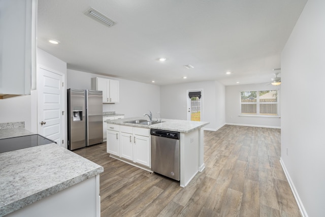 kitchen featuring appliances with stainless steel finishes, a sink, light wood-style flooring, white cabinets, and recessed lighting