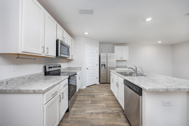 kitchen featuring appliances with stainless steel finishes, a sink, recessed lighting, light wood-style flooring, and white cabinets