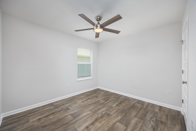 spare room featuring dark wood-style floors, a ceiling fan, and baseboards