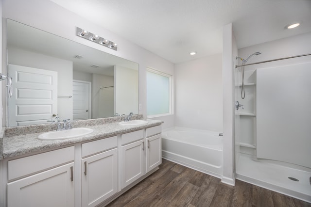 bathroom featuring wood finished floors, a shower, double vanity, and a garden tub