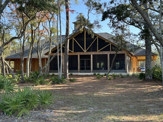 back of house with a sunroom and a shingled roof