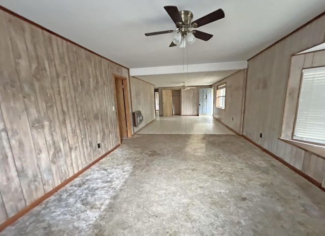spare room with a ceiling fan, wood walls, and heating unit