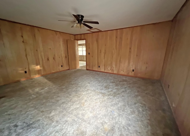 spare room featuring a ceiling fan and wood walls