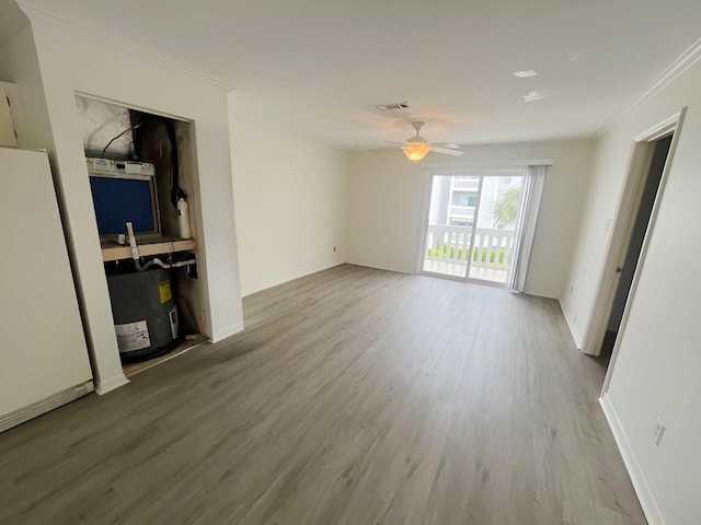 unfurnished living room with wood finished floors, ceiling fan, baseboards, and crown molding