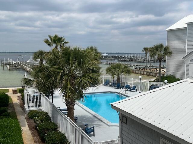 community pool featuring a water view, fence, and a patio area