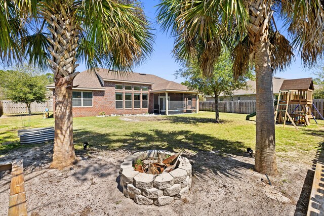 495 Brighton Cv, Freeport, FL 32439 - rear view of house featuring a sunroom, an outdoor fire pit, a playground, and brick siding