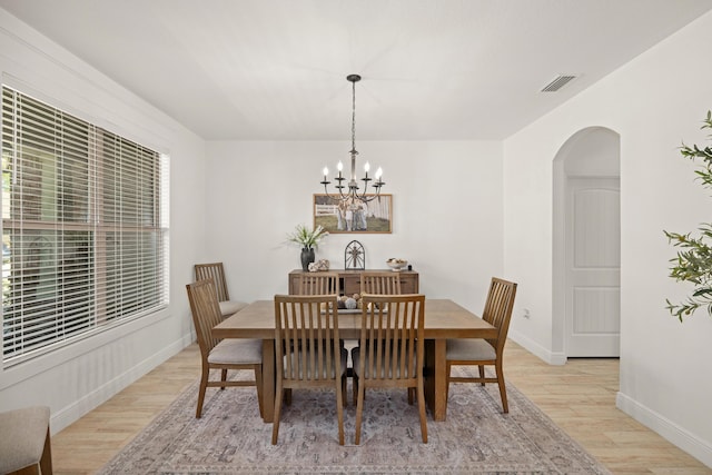 495 Brighton Cv, Freeport, FL 32439 - dining space with arched walkways, light wood-style flooring, a chandelier, and baseboards