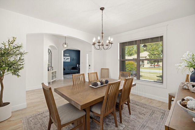 495 Brighton Cv, Freeport, FL 32439 - dining area with arched walkways, a chandelier, light wood-style flooring, and baseboards