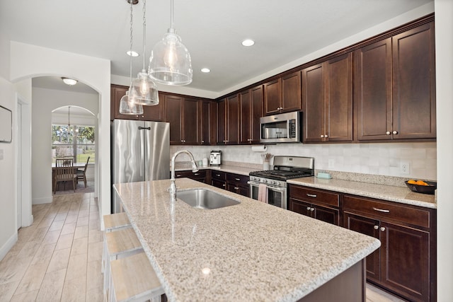 495 Brighton Cv, Freeport, FL 32439 - kitchen with appliances with stainless steel finishes, a sink, arched walkways, dark brown cabinetry, and pendant lighting