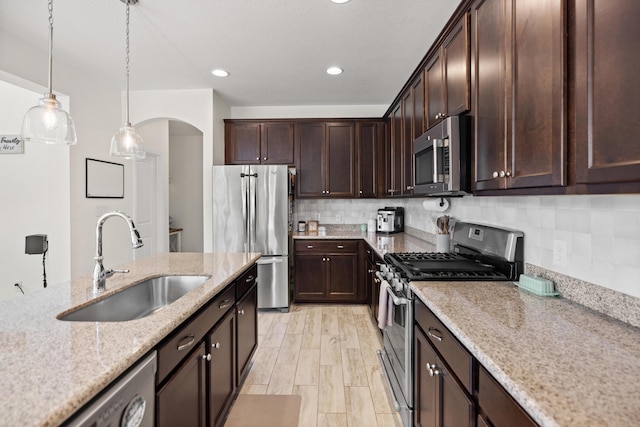 495 Brighton Cv, Freeport, FL 32439 - kitchen with stainless steel appliances, a sink, arched walkways, light stone counters, and dark brown cabinets