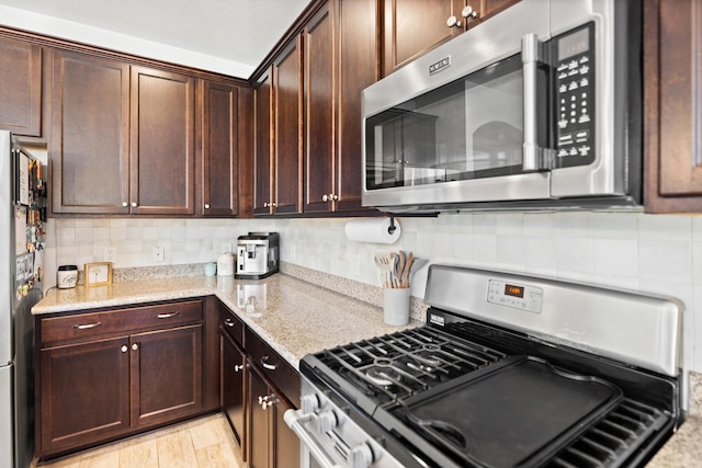 495 Brighton Cv, Freeport, FL 32439 - kitchen with appliances with stainless steel finishes, light stone counters, decorative backsplash, and dark brown cabinetry