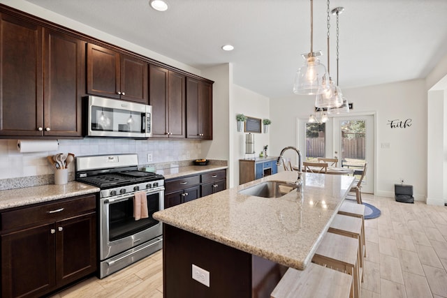 495 Brighton Cv, Freeport, FL 32439 - kitchen with stainless steel appliances, a sink, a kitchen breakfast bar, an island with sink, and light stone countertops