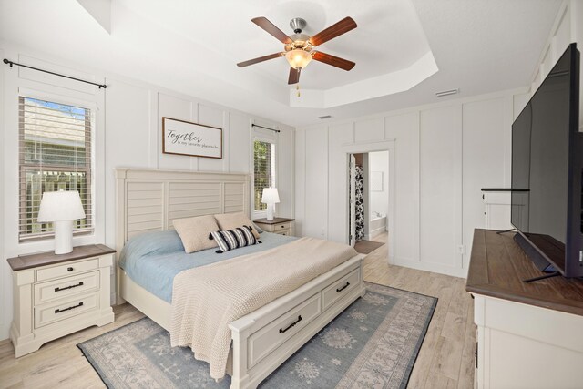 495 Brighton Cv, Freeport, FL 32439 - bedroom with a tray ceiling, a decorative wall, light wood-type flooring, ensuite bath, and ceiling fan