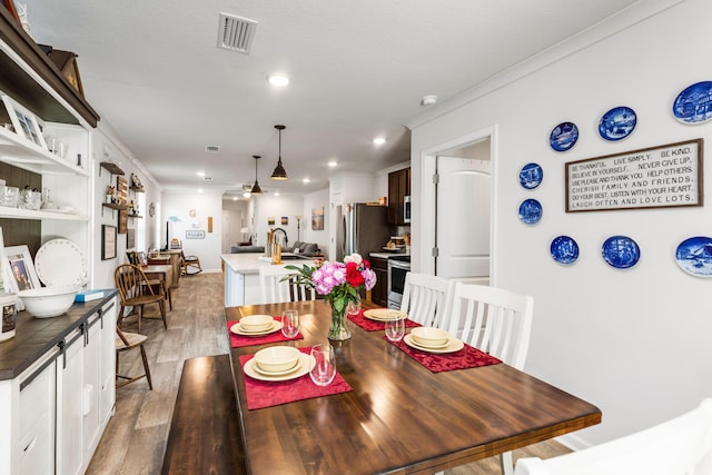 595 Earl Godwin Rd, Freeport, FL 32439 - dining space with light wood-style flooring, crown molding, and recessed lighting