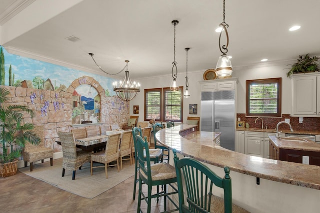 4701 Seastar Vis, Destin, FL 32541 - kitchen with stainless steel built in refrigerator, white cabinetry, light stone counters, crown molding, and a kitchen breakfast bar
