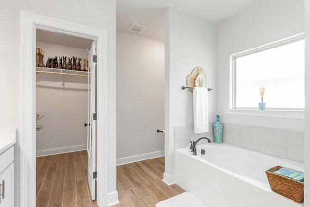 27 Cozy Cv, Freeport, FL 32439 - full bath with vanity, a garden tub, wood finished floors, and a walk in closet
