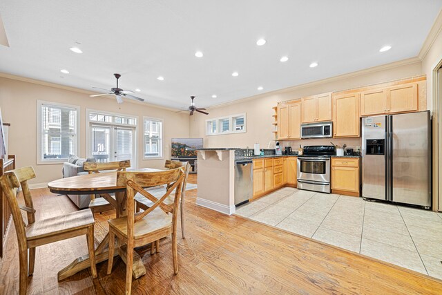 6236 Thomas Dr, Panama City Beach, FL 32408 - kitchen with stainless steel appliances, light brown cabinets, crown molding, a peninsula, and dark countertops