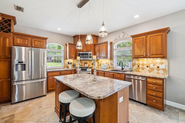 2009 Kildare Cir, Niceville, FL 32578 - kitchen featuring stainless steel appliances, a sink, a kitchen island, brown cabinets, and light stone countertops