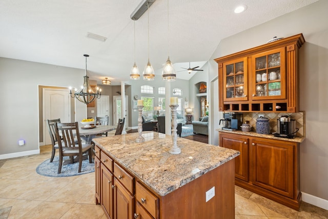 2009 Kildare Cir, Niceville, FL 32578 - kitchen featuring brown cabinets, a chandelier, a center island, light stone counters, and vaulted ceiling