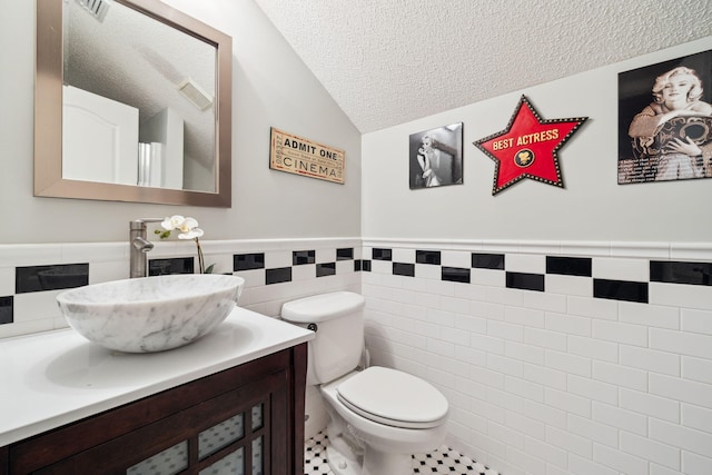 2009 Kildare Cir, Niceville, FL 32578 - bathroom featuring tile walls, a textured ceiling, vaulted ceiling, toilet, and vanity
