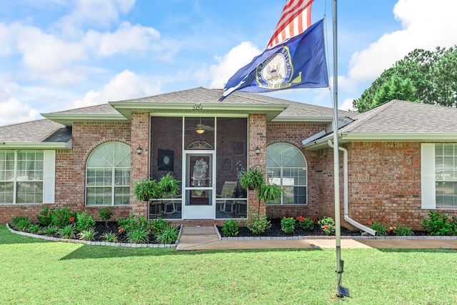 2424 Pineneedle Dr, Navarre, FL 32566 - property entrance with roof with shingles, a yard, and brick siding