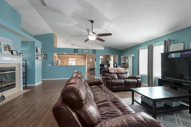104 Sandstone Trl, Crestview, FL 32539 - living area featuring lofted ceiling, a ceiling fan, wood finished floors, a textured ceiling, and a tiled fireplace