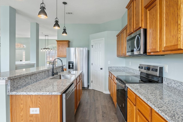 3167 Border Creek Dr, Crestview, FL 32539 - kitchen featuring appliances with stainless steel finishes, a sink, dark wood-style flooring, an island with sink, and light stone countertops