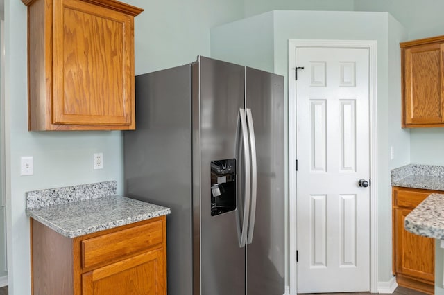 3167 Border Creek Dr, Crestview, FL 32539 - kitchen featuring stainless steel fridge, brown cabinetry, and light stone counters