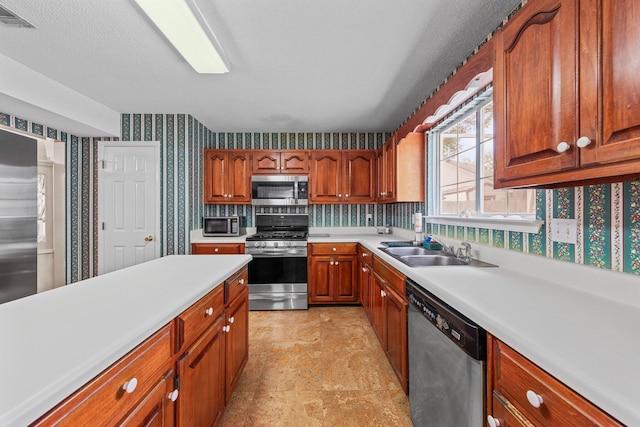 859 Mande Ct, Shalimar, FL 32579 - kitchen featuring stainless steel appliances, wallpapered walls, a sink, light countertops, and brown cabinets