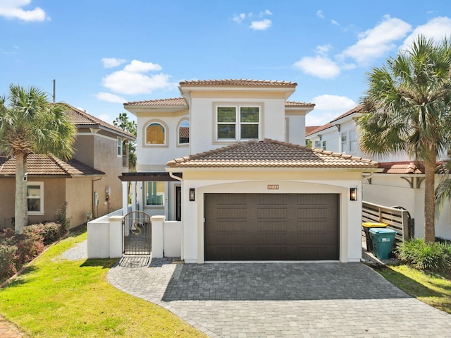 mediterranean / spanish home featuring decorative driveway, stucco siding, a gate, and a tile roof