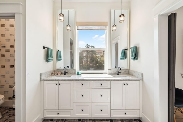 full bath featuring double vanity, baseboards, and toilet