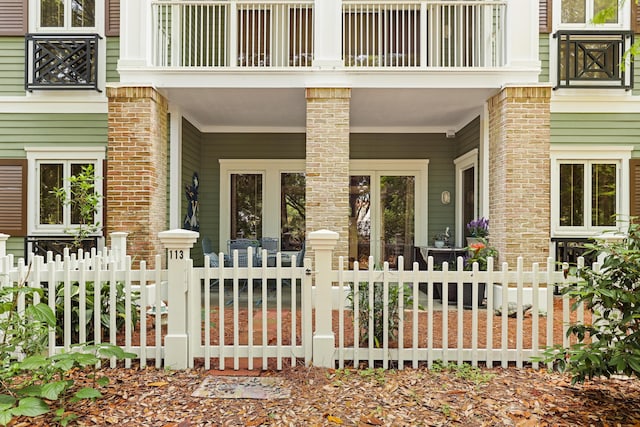 entrance to property with a porch, fence, and brick siding
