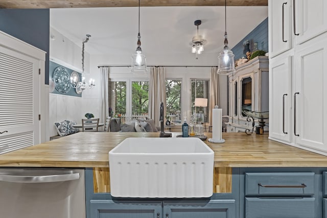 9300 Baytowne Wharf Blvd Unit 113, Miramar Beach, FL 32550 - kitchen featuring wooden counters, stainless steel dishwasher, a sink, blue cabinetry, and pendant lighting