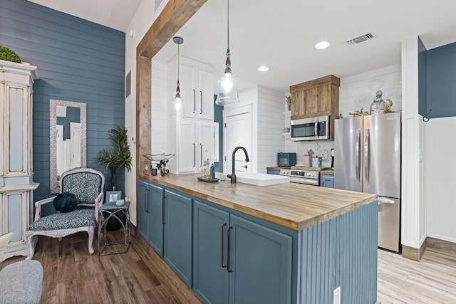 9300 Baytowne Wharf Blvd Unit 113, Miramar Beach, FL 32550 - kitchen featuring wooden counters, appliances with stainless steel finishes, a sink, a peninsula, and blue cabinets