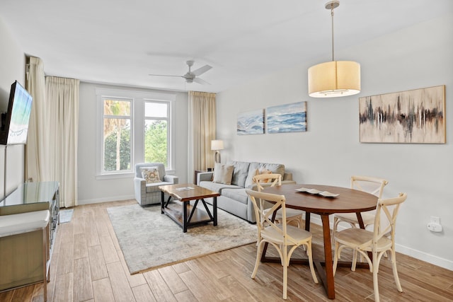 dining room featuring light wood-style flooring, ceiling fan, and baseboards