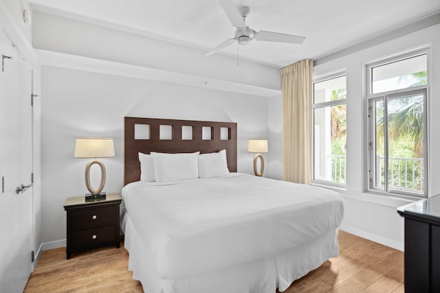 bedroom with multiple windows, light wood finished floors, baseboards, and ceiling fan