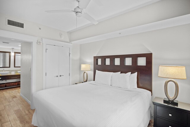 bedroom featuring light wood-type flooring, a closet, ensuite bathroom, and ceiling fan