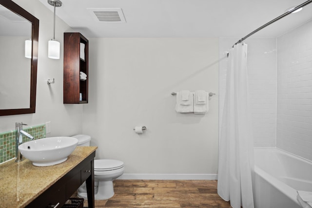 bathroom featuring wood finished floors, baseboards, toilet, vanity, and shower / tub combo with curtain
