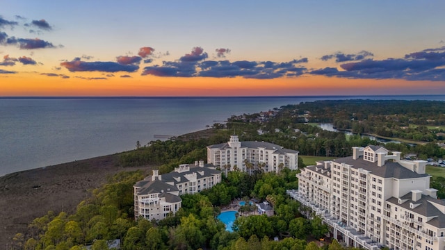 aerial view at dusk of a water view and view of pool area