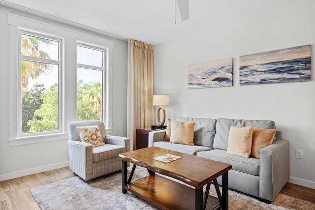 living area featuring plenty of natural light, light wood-style flooring, ceiling fan, and baseboards