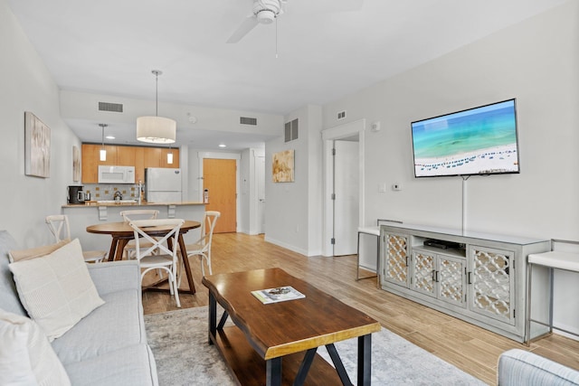 living room with light wood-style floors, ceiling fan, and baseboards