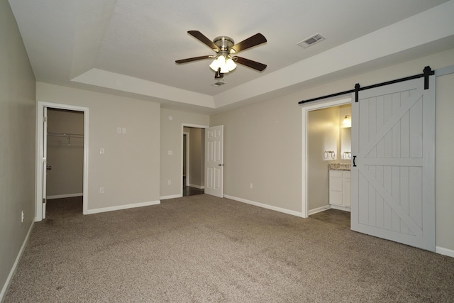 1422 Oakwood Lakes Blvd, Defuniak Springs, FL 32433 - unfurnished bedroom featuring a raised ceiling, carpet, baseboards, a barn door, and a walk in closet