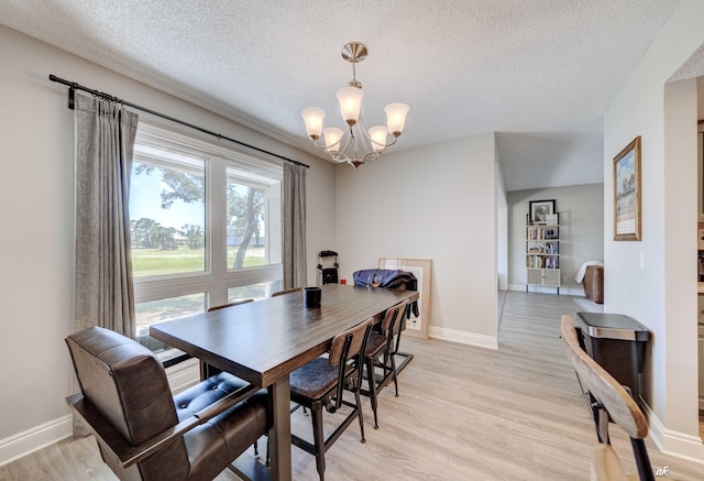 dining area featuring a chandelier, a textured ceiling, baseboards, and light wood-style flooring