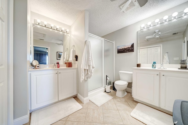 full bathroom featuring a shower stall, a ceiling fan, and two vanities