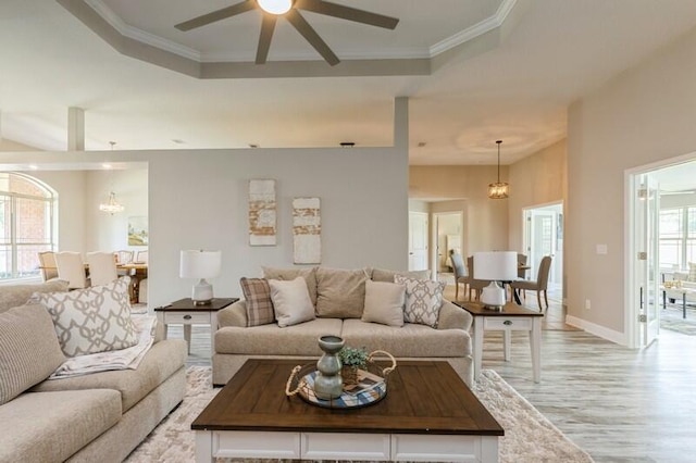 6216 Plum Orchard Way, Crestview, FL 32536 - living room featuring a ceiling fan, light wood finished floors, a tray ceiling, ornamental molding, and a chandelier