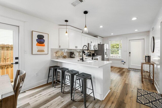 65 Brown St, Santa Rosa Beach, FL 32459 - kitchen with appliances with stainless steel finishes, wood finished floors, a breakfast bar area, white cabinets, and light countertops